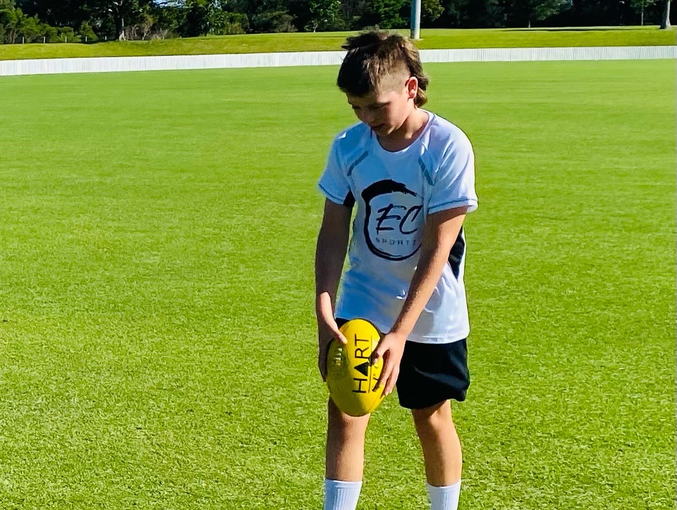 Young EC Sportz Academy player practising an AFL drop punt